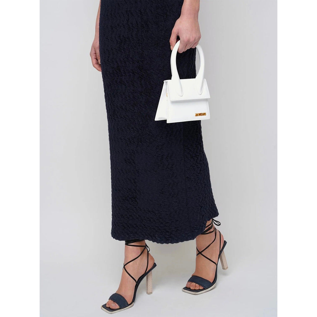 Jacquemus – Chiquito Moyen Leather Shoulder Bag – White bag carried by hand with dark outfit