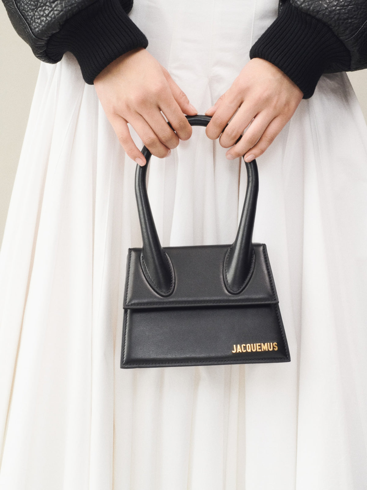 jacquemus – Chiquito Moyen Handbag in Black – held against a white dress